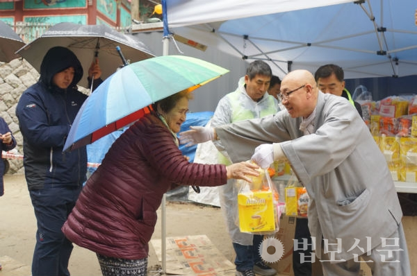 금곡 스님이 경로잔치를 찾은 어르신들에게 선물세트를 나눠주고 있다.