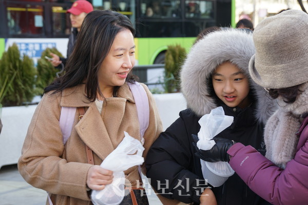 시민들이 팥죽을 받고 활짝 웃고 있다.