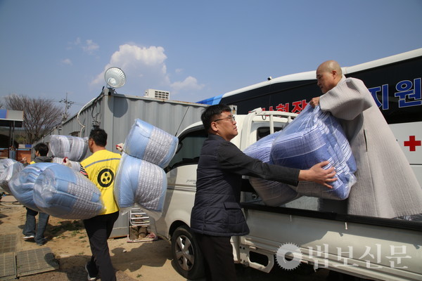  전국 각지에서 구비한 구호품을 옮기는 죽림정사 주지 일광 스님과 재단 관계자들.